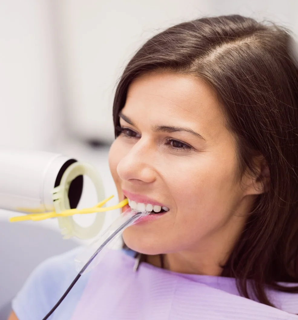 Dental consultation between a woman in scrubs and a man, discussing on a smartphone in a modern office setting.