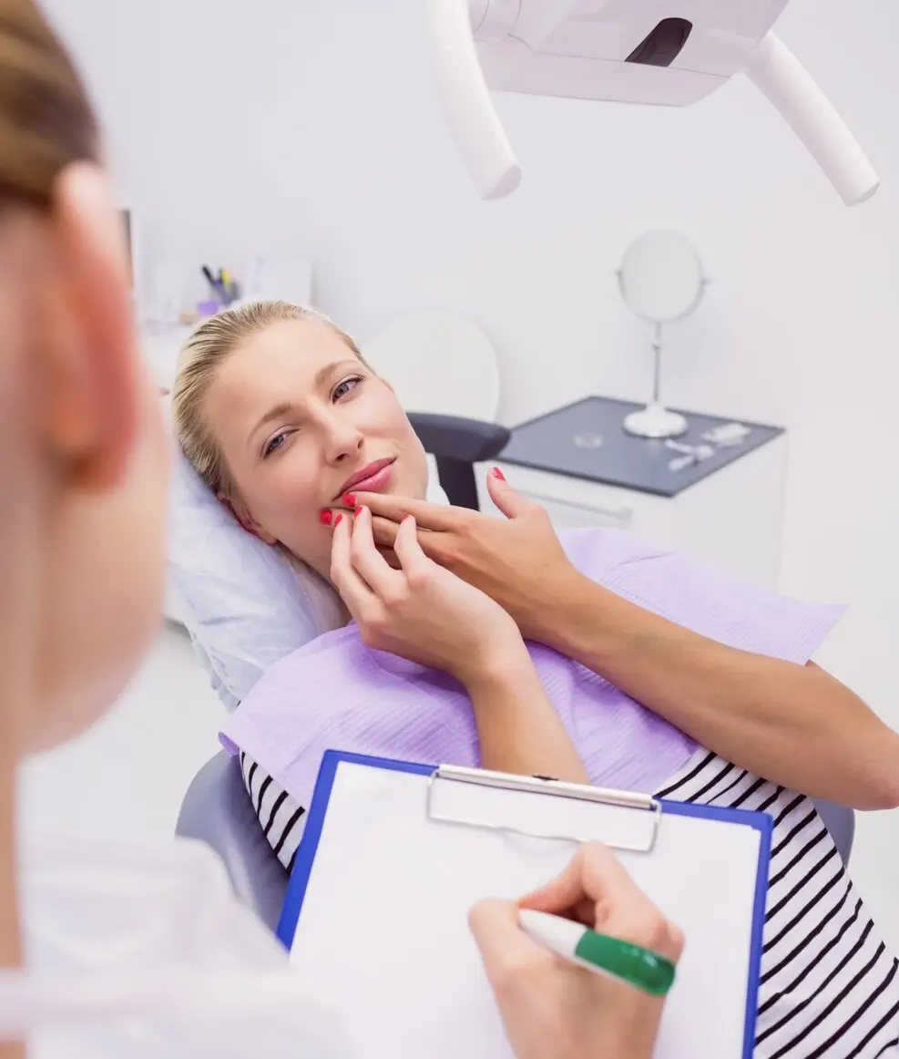 Dental consultation between a woman in scrubs and a man, discussing on a smartphone in a modern office setting.